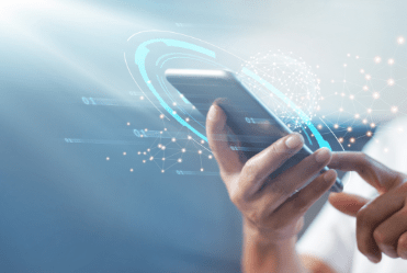 Eine Person hält ein Smartphone in der Hand und bedient das Display. Holographisch werden Daten dargestellt, die in das Gerät eingespeist werden.