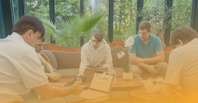 IT-Techniker und Kunden sitzen gemeinsam an einem Tisch, um die Ergebnisse einer IT-Analyse zu besprechen. Die IT-Infrastruktur des Kunden soll damit verbessert werden.